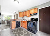 Thumbnail 2 of 40 - A modern kitchen with wooden cabinets and black appliances.