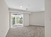 Thumbnail 7 of 32 - A room with a carpeted floor and a sliding glass door leading outside.