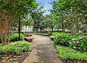 Thumbnail 64 of 66 - A garden with a concrete walkway and a variety of plants and trees.