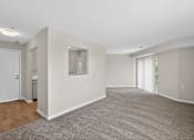 Thumbnail 8 of 32 - A spacious room with a carpeted floor and a door on the left side.