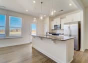 Thumbnail 2 of 20 - a kitchen with a large island and a stainless steel refrigerator