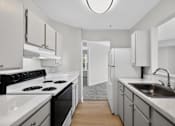 Thumbnail 14 of 32 - A modern kitchen with white appliances and cabinets.