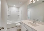 Thumbnail 11 of 16 - a bathroom with a white toilet next to a white bathtub