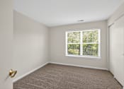 Thumbnail 6 of 32 - A room with a carpeted floor and a window showing trees outside.