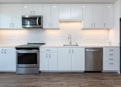 Thumbnail 2 of 20 - A modern kitchen with white cabinets and stainless steel appliances.