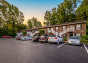 Thumbnail 1 of 17 - a parking lot with cars in front of an apartment building