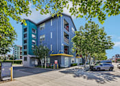 Thumbnail 1 of 24 - A blue and green building with a parking lot in front.