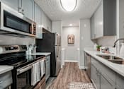 Thumbnail 2 of 34 - A kitchen with a black refrigerator and stove top oven.