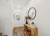 Thumbnail 28 of 45 - A hallway with a round mirror and a wooden bench.