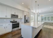 Thumbnail 1 of 14 - Luxury Three Bedroom Townhomes in Avondale Estates, GA – Henley Avondale – open kitchen with white cabinets and a large island