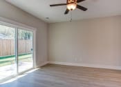 Thumbnail 11 of 25 - an empty living room with a sliding glass door and a ceiling fan