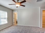 Thumbnail 9 of 25 - an empty living room with a ceiling fan and a window