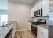 Thumbnail 4 of 62 - Three-Bedroom Homes for Rent in Myrtle Beach, SC - The Palmer at Carolina Forest - Kitchen with Granite Countertops, Stainless Steel Appliances, White Cabinets, and Vinyl Plank Flooring