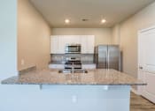 Thumbnail 48 of 62 - a kitchen with a granite counter top and a stainless steel refrigerator