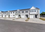 Thumbnail 2 of 45 - Townhomes for Rent in North Charleston, SC - Highland Townhomes - Street View of Townhomes with White and Grey Walls, Garages, and Spacious Concrete Driveways.