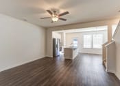 Thumbnail 41 of 45 - an empty living room with a ceiling fan and a kitchen