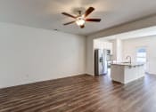 Thumbnail 42 of 45 - an empty living room with a kitchen and a ceiling fan
