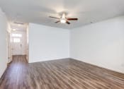 Thumbnail 39 of 45 - Four-BR Townhomes in North Charleston, SC - Highland Townhomes - Empty Living Room With White Walls, Wood-Style Flooring, and A Ceiling Fan