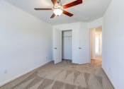 Thumbnail 27 of 45 - Three-Bedroom Townhomes in North Charleston, SC - Highland Townhomes - Carpeted Bedroom with White Walls, Ceiling Fan, and Large Closet.