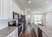 Thumbnail 7 of 45 - North Charleston, SC Townhomes Near Tanger Outlets - Highland Townhomes - Kitchen with Hardwood Floor, Stainless Steel Appliances, Granite Countertops, and White Cabinetry.