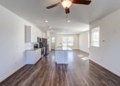 Thumbnail 22 of 45 - an empty living room with a ceiling fan and a kitchen