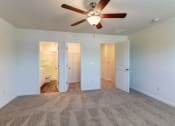 Thumbnail 14 of 45 - an empty living room with a ceiling fan and a door to a bathroom