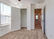 Thumbnail 9 of 45 - 4-BR Townhomes in North Charleston, SC - Highland Townhomes - Empty Bedroom With Carpet Flooring, A Large Window, White Walls, and A Closet