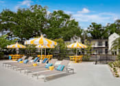 Thumbnail 7 of 34 - A sunny day at the pool with yellow umbrellas and lounge chairs.