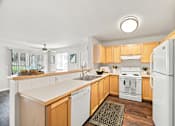 Thumbnail 9 of 47 - A kitchen with wooden cabinets and white appliances.