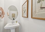 Thumbnail 43 of 45 - A bathroom with a sink, mirror, and two framed pictures on the wall.