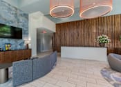 Thumbnail 10 of 24 - A reception area with a white reception desk and a TV mounted on the wall.
