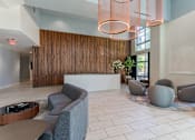 Thumbnail 11 of 24 - A reception area with grey couches and a wooden reception desk.