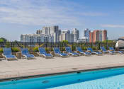 Thumbnail 32 of 46 - a row of lounge chairs next to a pool with a city in the background