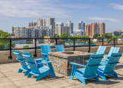 Thumbnail 28 of 46 - a deck with blue chairs and a fire pit with a view of the city
