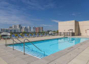 Thumbnail 30 of 46 - a pool on the roof of a building with a city in the background