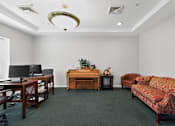 Thumbnail 18 of 32 - A room with a couch, desk, and chair.