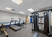 Thumbnail 31 of 47 - A gym with a variety of equipment including a treadmill, weights, and a squat rack.