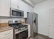 Thumbnail 8 of 24 - One-BR Apartments in Petaluma, CA - Theatre Square - Galley Kitchen With White Cabinets, Laminate Countertops, And Stainless-Steel Appliances Including Gas Range And Microwave.