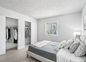 Thumbnail 8 of 34 - 1 Bedroom Apartments in North Mountain Village, Phoenix, AZ - Ardella on 28th - Bedroom with Wood-Style Flooring, Bed, Bedside Table with Lamp, Two Large Closets with Sliding Wood Doors, and Window.