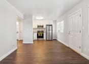Thumbnail 3 of 15 - A kitchen with white cabinets and a wooden floor.