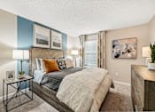 Thumbnail 13 of 34 - A bedroom with a bed, nightstand, and a painting on the wall.