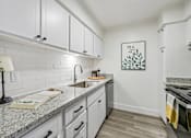 Thumbnail 30 of 34 - A kitchen with white cabinets and a granite countertop.