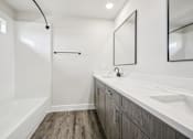 Thumbnail 35 of 47 - A modern bathroom with a white tub and wooden floors.