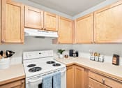 Thumbnail 7 of 47 - A kitchen with wooden cabinets and a white stove top oven.