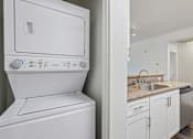 Thumbnail 13 of 24 - A white washing machine and dryer in a small kitchen.