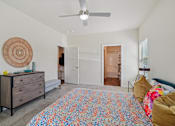 Thumbnail 12 of 39 - A bedroom with a colorful bedspread and a ceiling fan.