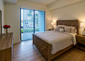 Thumbnail 7 of 36 - Spacious bedroom at Gateway Luxury Apartments in Pompano Beach, featuring large sliding glass doors that brings in abundant natural light.