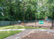 Thumbnail 15 of 25 - Sandy Springs, GA Apartments – Celebration at Sandy Springs - a  dog park with a fence and a playground in the background