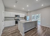 Thumbnail 5 of 21 - a kitchen with white cabinets and a large island with granite countertops