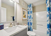Thumbnail 16 of 34 - A bathroom with a white sink, toilet, and shower curtain.